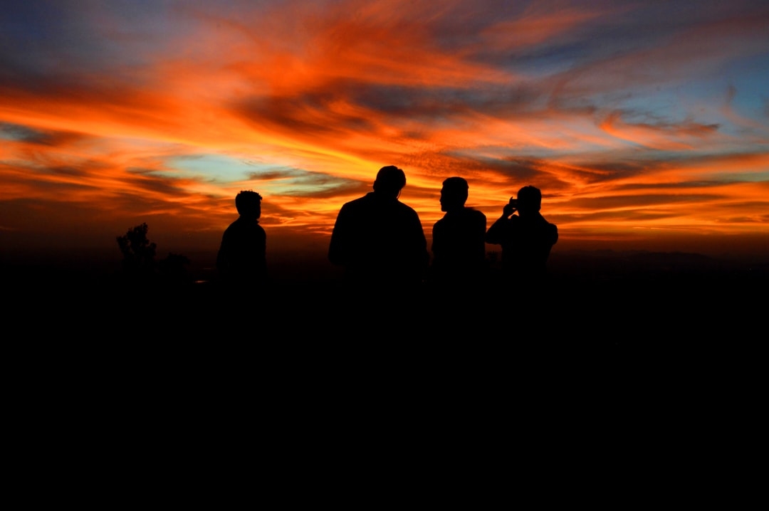 silhouette of four person under orange sky