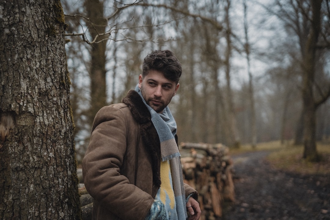 A man standing next to a tree in a forest