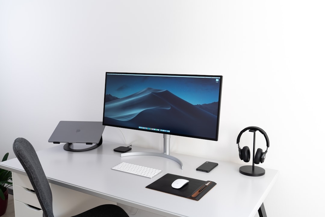 black flat widescreen computer monitor with Apple Magic Keyboard and mouse on desk