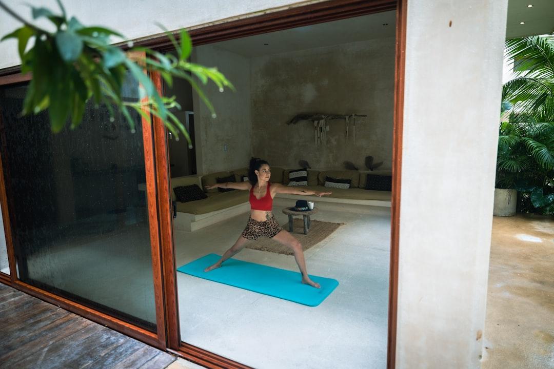 a woman in a red top doing yoga on a blue mat